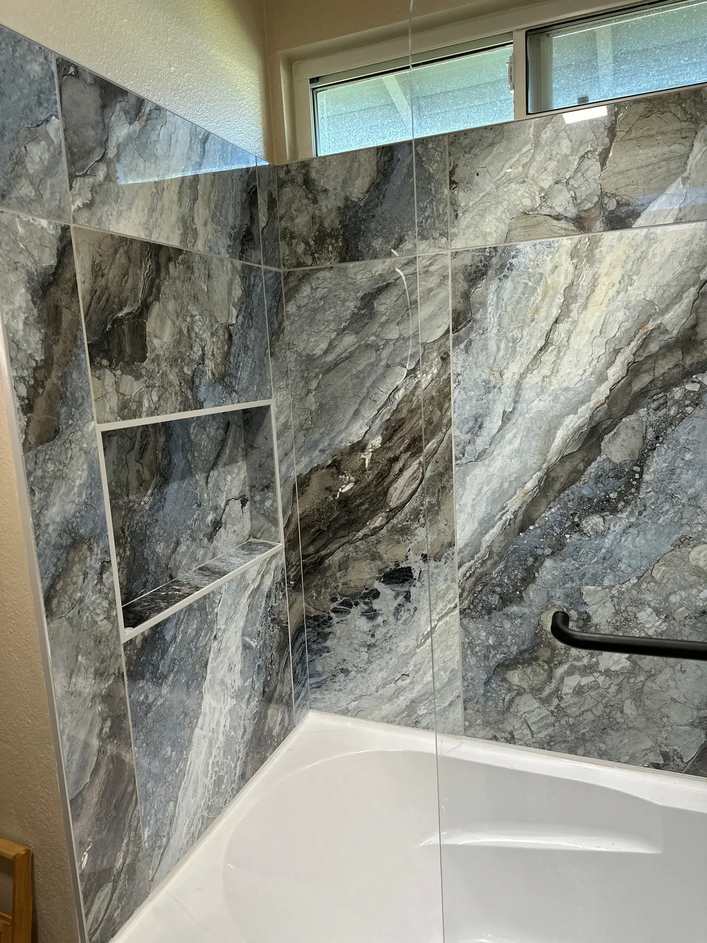 Luxurious marble tile bathtub surround with frosted window